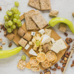 green-peppers-grapes-dried-fruits-crackers-crisp-bread-cheese-blocks-wooden-desk