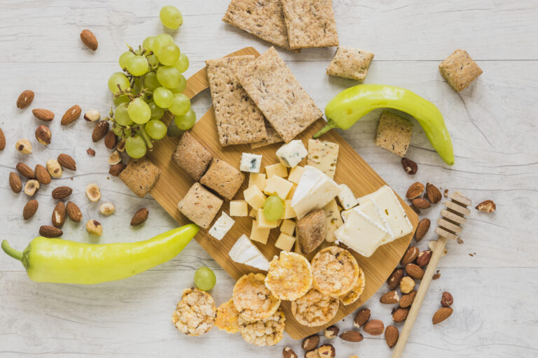 green-peppers-grapes-dried-fruits-crackers-crisp-bread-cheese-blocks-wooden-desk