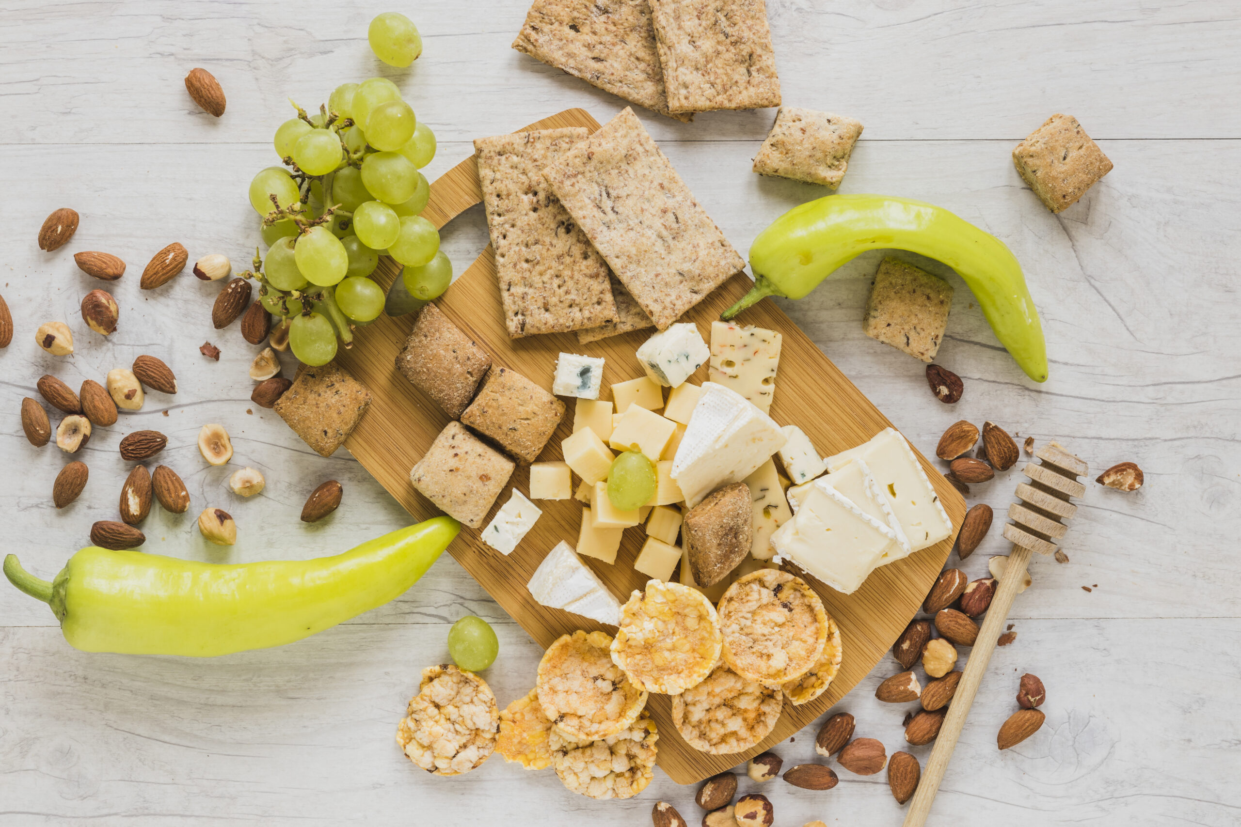 green-peppers-grapes-dried-fruits-crackers-crisp-bread-cheese-blocks-wooden-desk